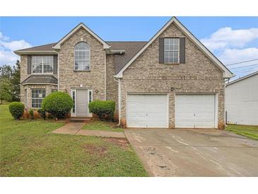 Traditional two-story brick home featuring an attached two-car garage, arched window, and manicured landscaping at 5080 Galleon Xing, Decatur, GA 30035