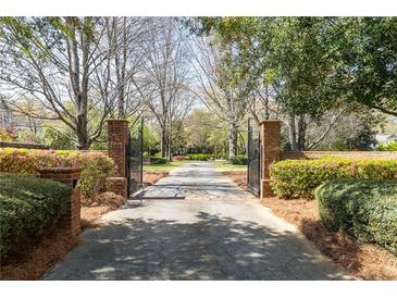 Gated driveway entrance with brick pillars, lush landscaping, and mature trees leads to the estate at 3847 Sweet Bottom Dr, Duluth, GA 30096