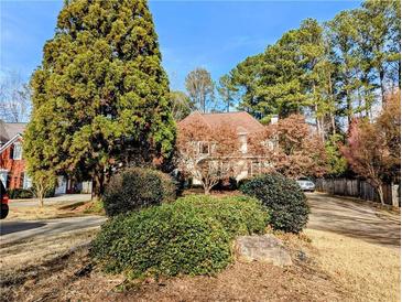 Charming home exterior featuring mature trees, lush landscaping, and a well-maintained lawn at 3655 Brisbane Dr, Marietta, GA 30062