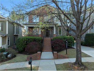 Charming two-story brick home featuring a covered front porch and meticulously landscaped front yard with mature trees at 2019 Mason Mill Rd, Decatur, GA 30033