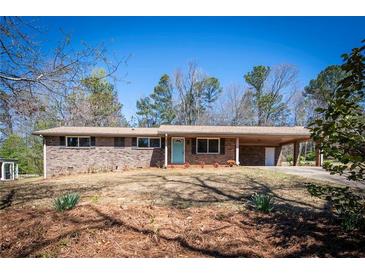Charming brick home with a light blue door, covered parking, and a well-maintained front lawn at 6175 Marilla St, Douglasville, GA 30135