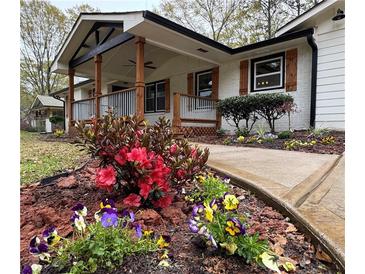 Charming home with a covered porch and beautifully landscaped front yard with colorful flowers at 3533 Johns Rd, Tucker, GA 30084