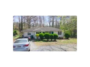 Charming single story home with a driveway and green shrubs in front of the house at 5077 Redan Rd, Stone Mountain, GA 30088