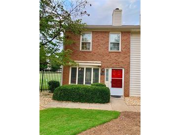 Charming brick townhouse featuring a well-manicured lawn and vibrant red front door at 988 Old Holcomb Bridge Rd, Roswell, GA 30076