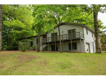 Two-story house with white painted brick, wooden deck, and lush trees surrounding the home at 5384 Blackhawk Dr, Acworth, GA 30102