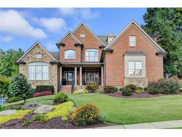 Beautiful brick home featuring manicured lawn, colorful flowerbeds, and stone accents at 3006 Cambridge Hill Dr, Dacula, GA 30019