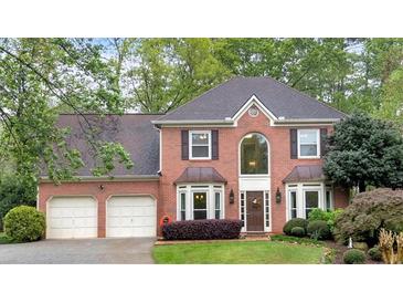 Charming two-story red brick home with an attached two-car garage and beautifully landscaped front yard at 3951 Lorien Nw Way, Kennesaw, GA 30152