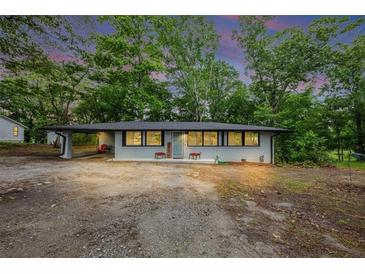 Charming single-story home with a covered parking area surrounded by mature trees and a gravel driveway at 8065 Highway 92 Dallas, Douglasville, GA 30134