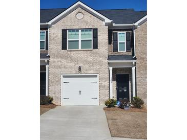 Charming two-story townhouse with brick facade, one-car garage, and manicured landscaping at 1302 Speckle Park Way, Stockbridge, GA 30281