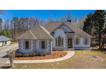 Charming single-story home boasting unique architectural details, neutral color palette, and well-manicured landscaping at 7025 Bavarian Wood Pl, Buford, GA 30518