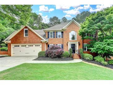 Beautiful brick home featuring a manicured lawn, two-car garage, and mature trees at 10835 Tuxford Dr, Alpharetta, GA 30022