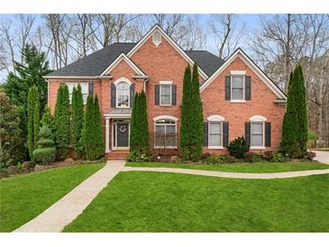 Elegant brick home with manicured lawn, tall evergreens, and a welcoming front entrance at 2611 Winterthur Main Nw, Kennesaw, GA 30144