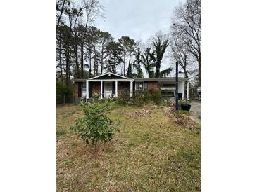 Modest one-story home with brick facade, covered front porch, and mature trees in the front yard at 4438 Ryan Rd, Conley, GA 30288