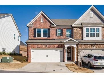 Charming brick townhome featuring a two-car garage and well-manicured lawn at 1042 Edwin Ln, Sugar Hill, GA 30518