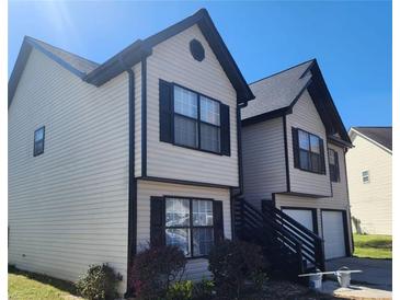 Two-story home featuring tan siding, black shutters, and a driveway leading to a single-car garage at 4080 Brushymill Ct, Loganville, GA 30052