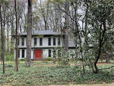 Charming home with a bright red front door nestled among mature trees and lush greenery at 257 Forest Lake Rd, Lawrenceville, GA 30046