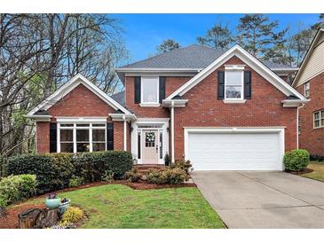 Charming brick home featuring a manicured lawn, two-car garage, and traditional architectural details at 4236 Providence Ln, Tucker, GA 30084