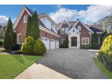 Beautiful brick home featuring a three-car garage, manicured lawn, and a spacious driveway at 821 Camden Park Ct, Atlanta, GA 30342