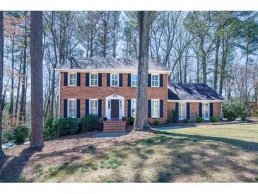 Charming two-story brick home featuring black shutters, a well-manicured lawn, and mature trees at 725 Glengary Ne Way, Atlanta, GA 30342