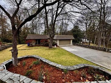 Charming single-story home featuring a well-manicured lawn and a paved driveway leading to an attached garage at 1075 Winding Branch Ln, Atlanta, GA 30338