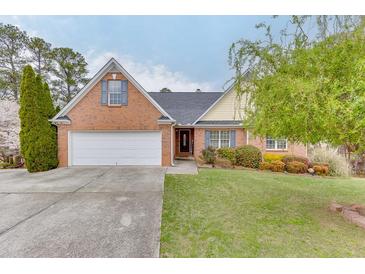 Charming brick home featuring a well-manicured lawn, mature trees, and attached two-car garage at 802 Towering Pine Trl, Lawrenceville, GA 30045