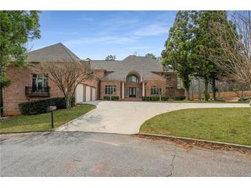 Stately brick home with a circular driveway, mature trees and three-car garage at 1483 Jones Rd, Roswell, GA 30075