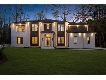 Elegant two-story home featuring a lush lawn, brick facade, dark trim, and inviting entryway at 942 Fairfield Dr, Marietta, GA 30068