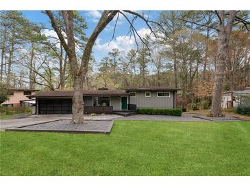 Charming single-story home featuring a well-manicured lawn, modern gray paint, and a two-car garage at 3473 Regalwoods Dr, Atlanta, GA 30340