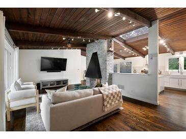 Cozy living room featuring a brick fireplace, wood ceiling beams, and modern decor open to a kitchen at 3473 Regalwoods Dr, Atlanta, GA 30340
