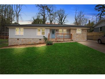 Charming one-story home featuring a stone and brick facade, well-manicured lawn, and welcoming front porch at 1752 Atherton Dr, Decatur, GA 30035