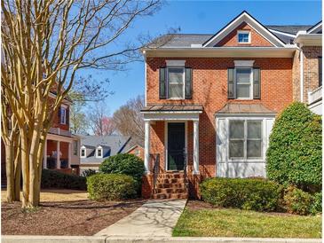 Charming two-story red brick townhouse with manicured landscaping and inviting front porch at 5210 Davenport Pl, Roswell, GA 30075