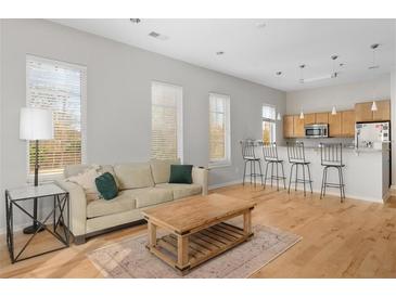 Bright living room with hardwood floors, sofa, area rug, large windows, and an open floorplan with the kitchen and breakfast bar at 1430 Dresden Ne Dr # 215, Atlanta, GA 30319