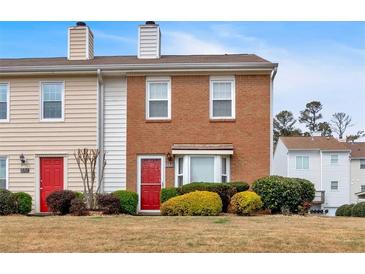 Charming townhome featuring a red front door and well-maintained landscaping at 219 Holcomb Ferry Rd, Roswell, GA 30076