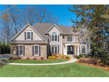 Charming home featuring stone accents, gray siding, manicured lawn, and beautiful landscaping at 5303 Whitehaven Park Se Ln, Smyrna, GA 30126
