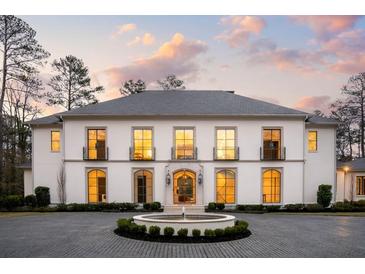 Elegant two-story home with a circular driveway and fountain, complemented by manicured landscaping at 5245 Kenbrook Way, Sandy Springs, GA 30327