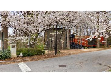 Unique home design with blooming trees in a wooded setting, featuring multi-level decks and a combination of wood and brick finishes at 595 Overbrook Nw Dr, Atlanta, GA 30318