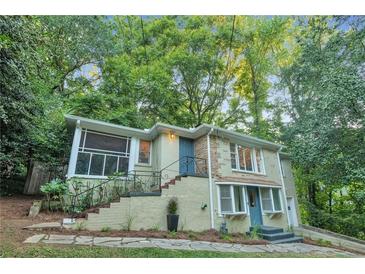Charming home exterior features a screened in porch, brick accents, and a lush surrounding of mature trees at 656 Channing Nw Dr, Atlanta, GA 30318