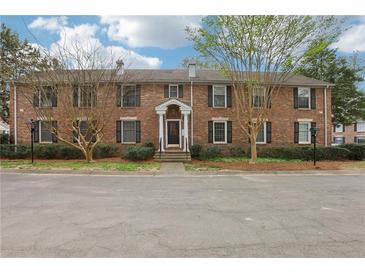 Charming brick townhouse featuring a well-maintained lawn, mature trees, and classic architectural details at 6700 Roswell Rd # 14C, Atlanta, GA 30328