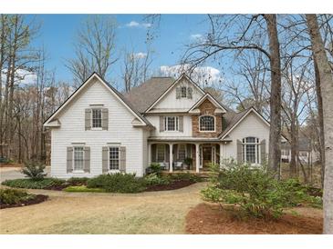 Charming two-story traditional home with stone accents, gabled roof, manicured lawn, and inviting front porch at 1270 Smokehouse Trl, Cumming, GA 30041