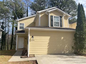 Charming two-story home features a bright yellow facade and well-maintained landscaping at 1374 To Lani Farm Rd, Stone Mountain, GA 30083