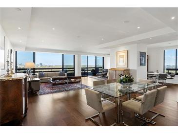 Bright living room and dining area feature hardwood floors and large windows with city views at 2660 Peachtree Nw Rd # 26F, Atlanta, GA 30305