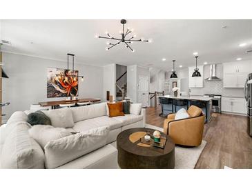 Bright living room showcasing a large sectional, modern light fixture, and open layout to the kitchen and dining area at 234 Retreat Ln, Canton, GA 30114