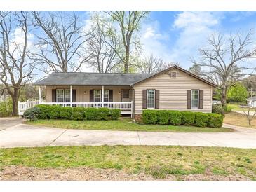 Charming single-story home with a covered front porch, complemented by mature landscaping and a spacious driveway at 2285 Bascomb Carmel Rd, Woodstock, GA 30189