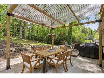Covered patio area featuring a wood table with seating, a grill, and a lush green backdrop at 205 Glencourtney Dr, Sandy Springs, GA 30328