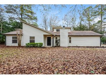 Traditional single-story home with white siding, black door, chimney, and a lawn covered in fall leaves at 2938 Parkwood Rd, Snellville, GA 30039