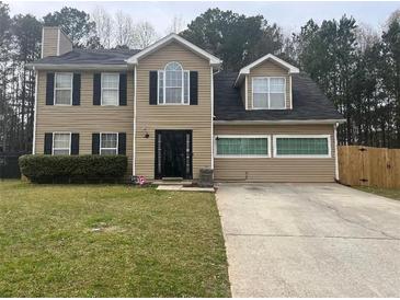 Two-story home with tan siding, a black front door, and a well-maintained front lawn at 2469 Briar Knoll Rd, Lithonia, GA 30058