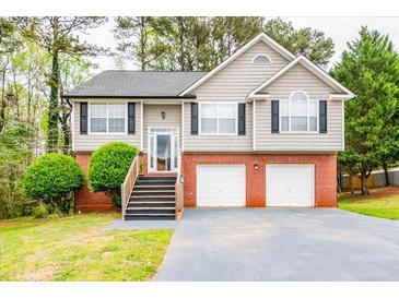 Charming two-story home with gray siding, brick foundation, and a two-car garage at 7617 Lakemoor Dr, Riverdale, GA 30296