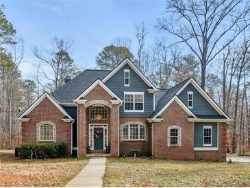 Beautiful two-story home featuring a brick facade, a welcoming front porch and mature trees in a tranquil landscape at 355 Parker Rd, Covington, GA 30014