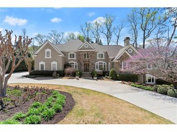 Stately stone and stucco home with well-manicured landscaping and circular driveway at 303 Rolling Rock Se Rd, Marietta, GA 30067