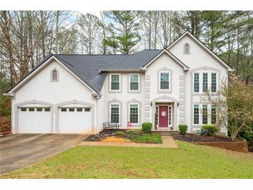 Charming two-story home with a well-manicured lawn, three-car garage, and attractive architectural details at 4057 Watkins Glen Dr, Woodstock, GA 30189